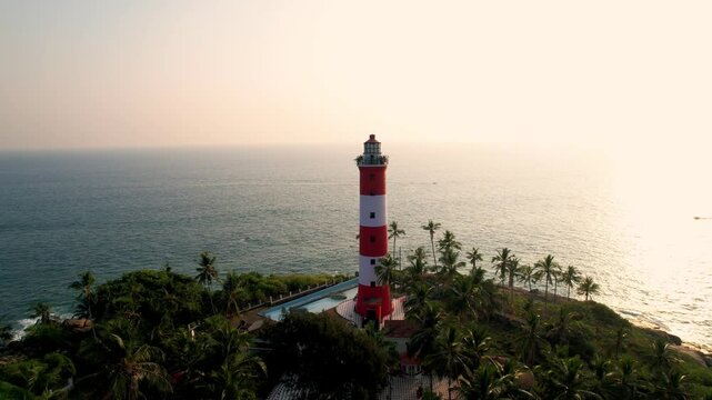 Lighthouse tower on a rocky coastline at sunset, Aerial View. Kovalam Beach whith Lighthouse in India, Kerala.