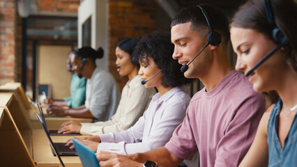Multi-Cultural Customer Support Or Telesales Team In Modern Open Plan Office Wearing Headsets