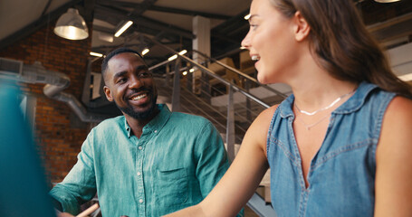 Male And Female Businesspeople Meeting In Office Working On Laptop With Colleagues In Background