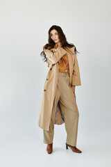 A young woman models a chic autumn outfit, featuring a stylish trench coat and tailored pants,...