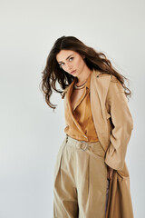 A young and beautiful woman models a chic autumn outfit, exuding elegance and confidence in a minimalistic studio backdrop.