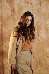 Fototapeta premium A young and beautiful woman smiles while posing in a chic autumnal outfit, embodying seasonal elegance and style.