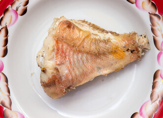 A piece of fried fish on a plate.