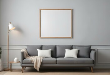 A modern living room with a gray sofa, white walls, and a large empty wooden frame on the wall.