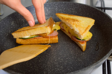 Woman hands cooking frying taking sandwiches from skillet on kitchen at home. Cook tasty meal, food, dish with white bread toasts. Ingredient recipe cuisine culinary. Homemade fast food preparing.