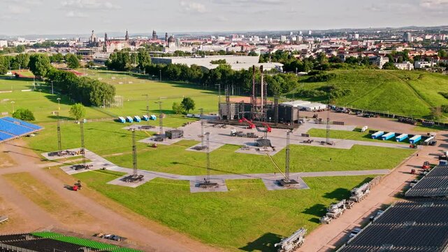 Drone video of a massive stage being set up for a RAMMSTEIN concert. construction process and the scale of the stage, highlighting the vibrant event preparations. Drone move forward.