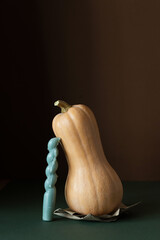Butternut squash with candle standing on kraft paper on dark background. Minimalist composition...