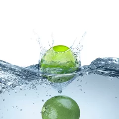 Tableau sur plexiglas  Fresh limes falling into water against white background  © New Africa
