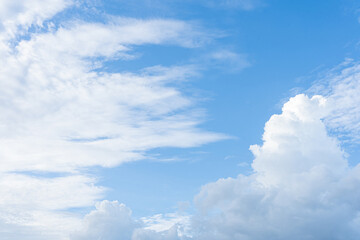 Fototapeta premium Fluffy cumulus clouds drift across a vibrant blue sky, casting soft shadows on the Earth below
