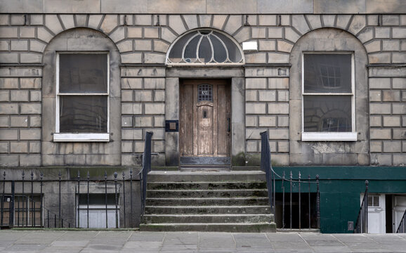 Georgian architecture of House in Edinburgh. Facade of Traditional house with sash windows, wooden doorway, stone stairs and wrought iron black railings, Copy space, Selective focus.
