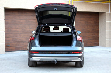 Modern car with open empty trunk outdoors. Black car is ready to load luggage. Clean trunk wagon...