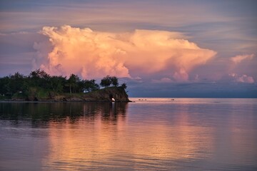Stunning colorful clouds during sunset on the Yasawa Islands, Fiji. Colorful sunset sky. Impressive clouds over a small island during golden hour. Orange and purple clouds reflecting in the water. 