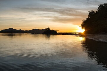 Bright sunset sky over deep blue water. Peaceful sunset scene on the Yasawa Islands, Fiji. Small islands during sunset. Tiny calm waves in front of the dark hills of a nearby island. Vacation paradise