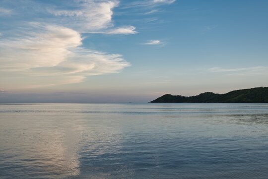 A beautiful sunset sky on a small Island of Fiji. Lovely reflections of the clouds and sky in the flat ocean water. Calm evening ocean scene with reflections of clouds and small islands. Yasawa Island