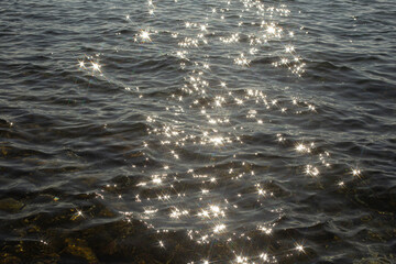 reflection sparkles on tiny ripples of sea water wave background, top view.