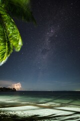 Fiji small island night scene. Tropical beach at night with thunderstorm and lightning in the background. Yasawa islands, Fiji, beach night. Thunder and lightning on a beach with stars and milky way. 