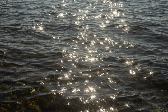 reflection sparkles on tiny ripples of sea water wave background, top view.
