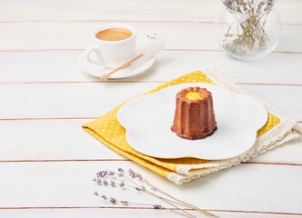 Dessert, canele with lemon curd on a white plate on a light wooden background.