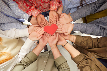 Top view of multiethnic people hands holding red paper heart symbol. Group of people standing in...