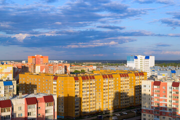 Fototapeta premium Top view of the city in the light of the sun under a cloudy sky at sunset