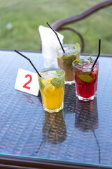 Four different colored drinks with straws in them sit on a table