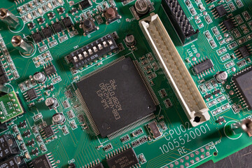 Square black processor on a green board.
