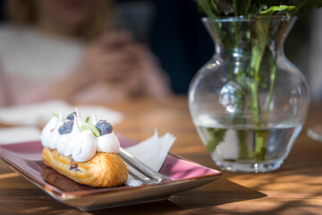 A pastry with whipped cream and blueberries sits on a plate on a table