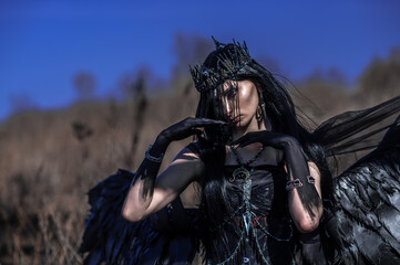 Obraz premium Goddess of death with black wings on a dried field