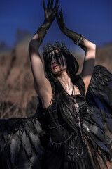 Naklejka premium Goddess of death with black wings on a dried field