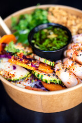 A vibrant poke bowl filled with fresh shrimp, cucumber, carrots, and herbs, topped with sesame seeds and chili flakes. Served with a flavorful dressing, this colorful dish is both healthy.