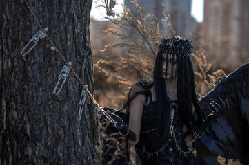 Naklejka premium Goddess of death with black wings on a dried field