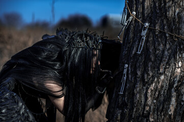 Naklejka premium Goddess of death with black wings on a dried field