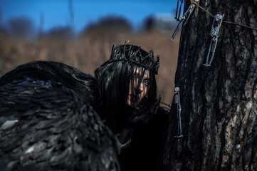 Goddess of death with black wings on a dried field