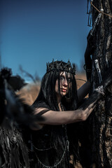 Naklejka premium Goddess of death with black wings on a dried field