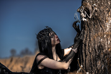 Goddess of death with black wings on a dried field