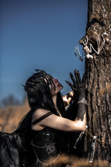 Goddess of death with black wings on a dried field
