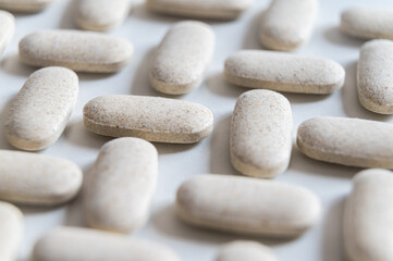 Medical tablets, placed next to each other on a white surface. Therapies, medicines and supplements.