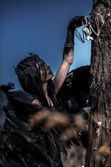 Naklejka premium Goddess of death with black wings on a dried field