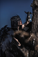 Goddess of death with black wings on a dried field