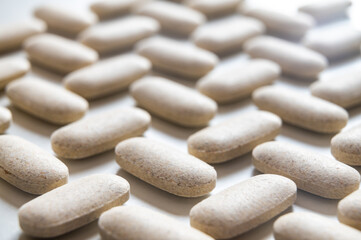 Medical tablets, placed next to each other on a white surface. Therapies, medicines and supplements.