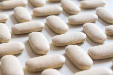 Medical tablets, placed next to each other on a white surface. Therapies, medicines and supplements.