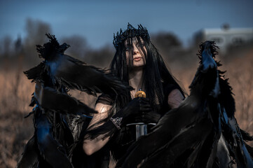 Obraz premium Goddess of death with black wings on a dried field