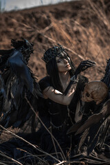 Goddess of death with black wings on a dried field