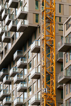 A high-rise building with numerous balconies is partially obscured by a yellow crane, highlighting the constant development in urban environments in Rotterdam