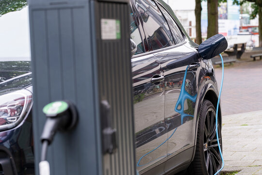 A sleek electric car charging at a public station in downtown, illustrating modern eco-friendly transportation and the adoption of green technology in urban environments.