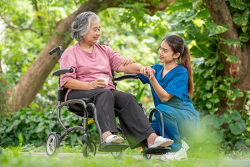 Elderly woman in a wheelchair holding a cup of milk young healthcare worker stands assisting take care providing drink interaction reflects attentive caregiving, support is healthy treatment concept.