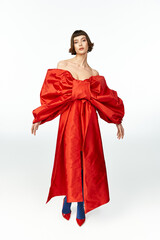 A stunning woman showcases a bold red dress with an oversized bow.