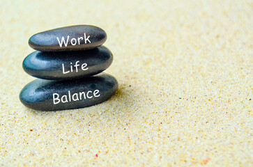 Work life balance text on black zen stones on sandy beach. Culture of work life balance concept.