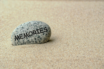 Memories text on stone buried in the sand