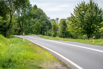 Fototapeta premium An asphalt road going through a forest in Masuria